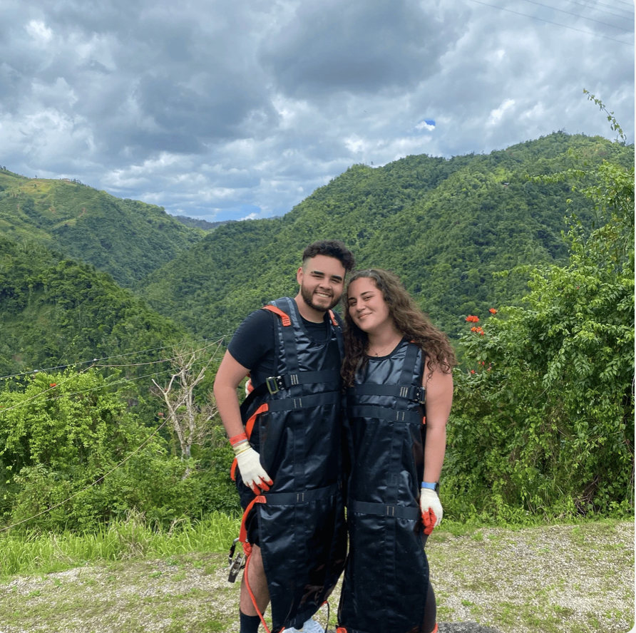 Nicole and Edwin together, smiling in their ziplining harnesses outdoors